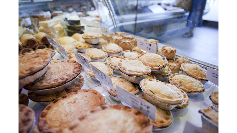 Variety of fresh meat pies in refrigerator at butchers shop