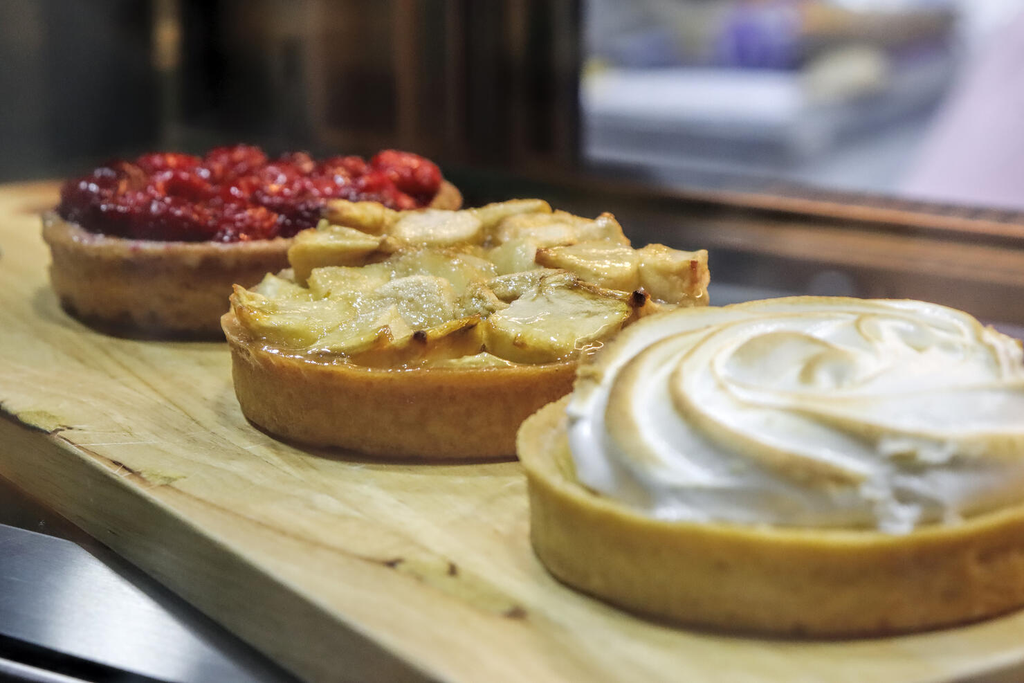 Side view of a fridge display with fruits tarts in a bakery shop