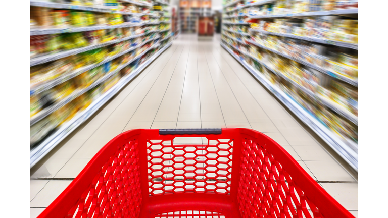 Red empty shopping cart in a supermarket aisle, motion blur