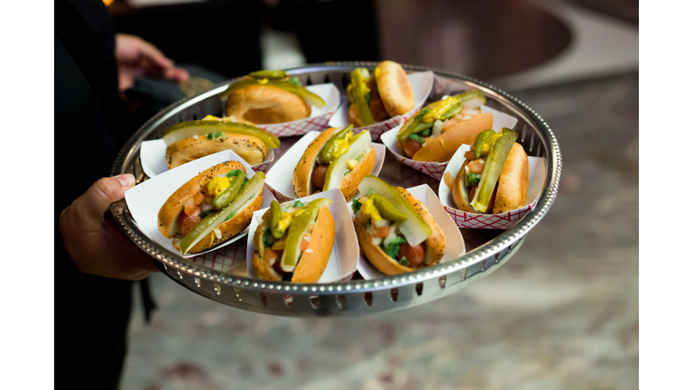 Server Holding A Tray of Mini Chicago Style Hot Dogs