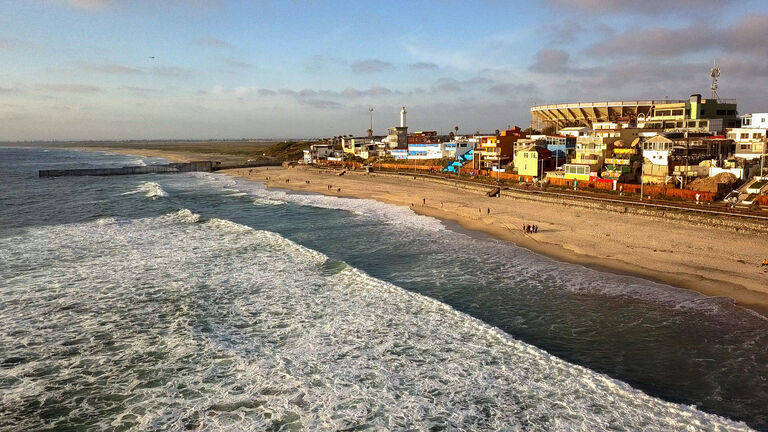 Sweeping Drone Point Of View Of The Beach And Boardwalk Near The International Border Wall In Playas Tijuana, Mexico