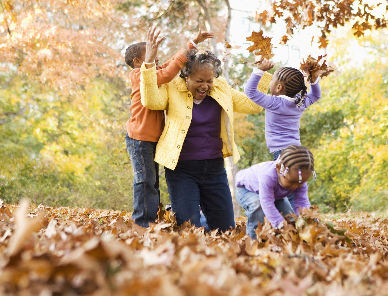 Grandmother and grandsons playing with leaves