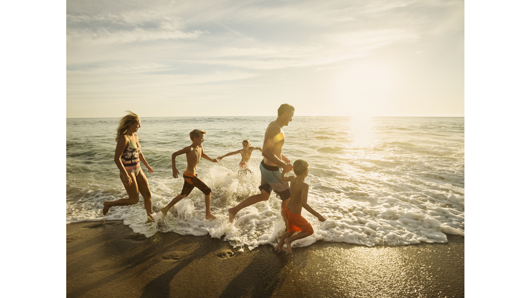 USA, California, Laguna Beach, Family with three children (6-7, 10-11, 14-15) running on beach