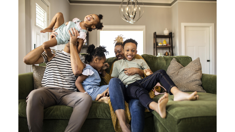 Family of five playing on sofa at home