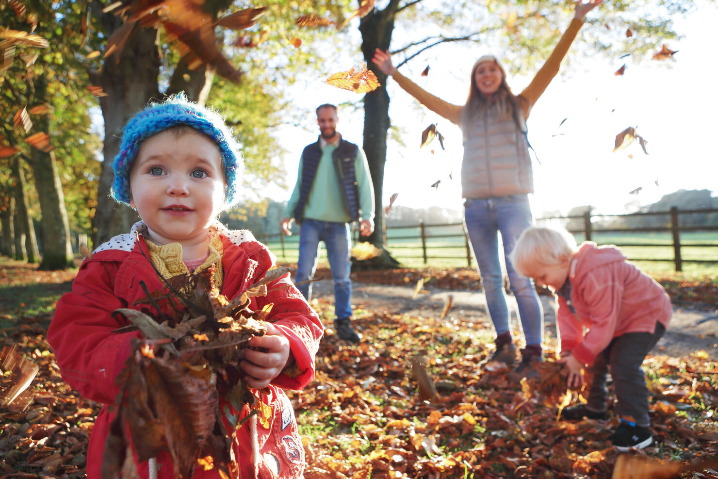 Family playing with fallen leaves in park