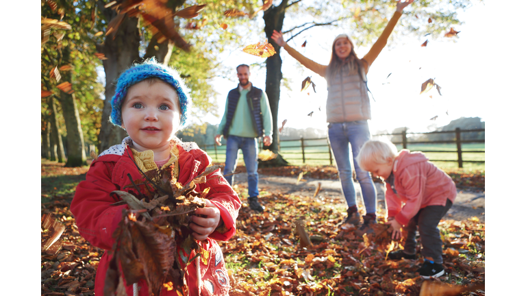 Family playing with fallen leaves in park