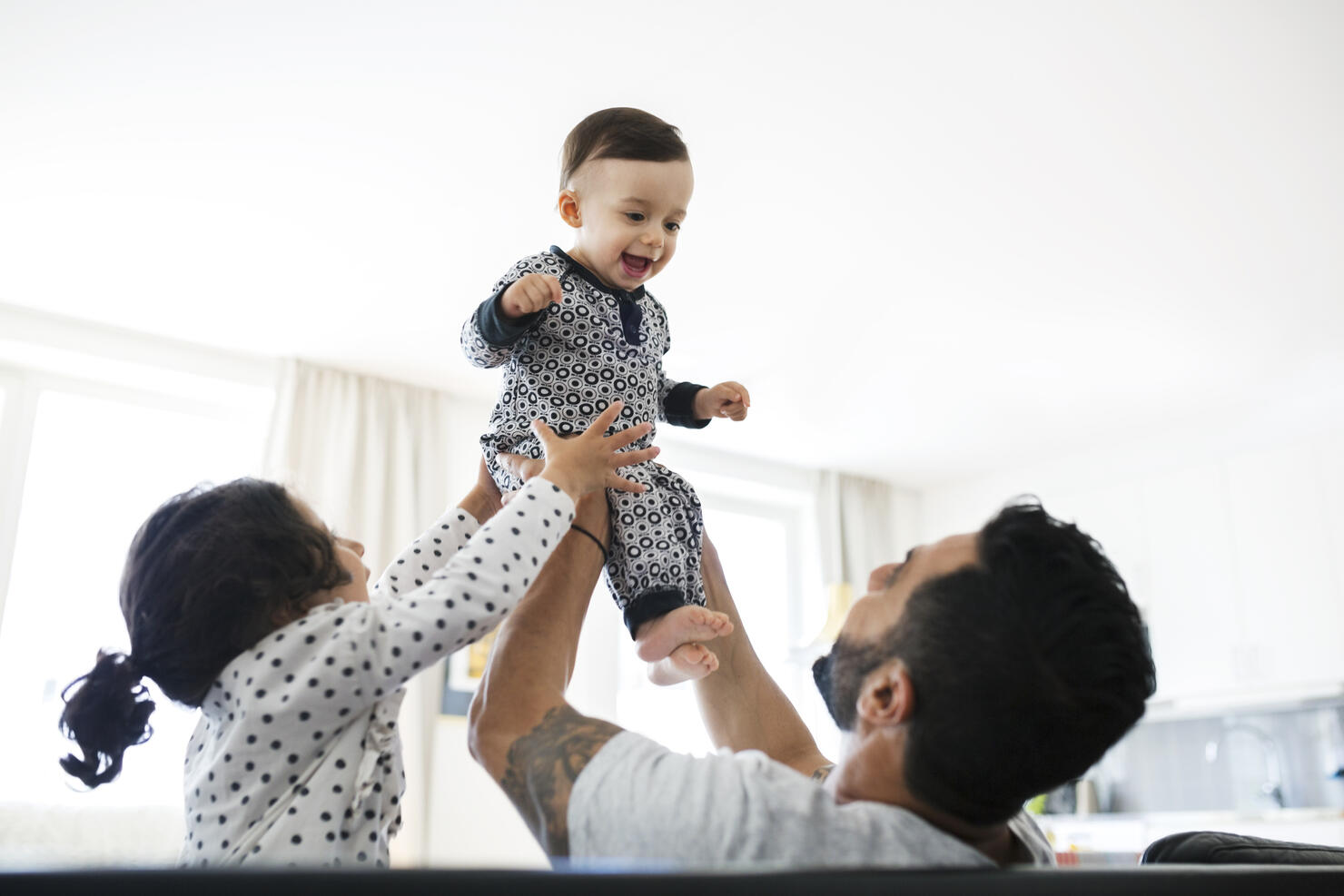Father and daughter lifting toddler at home