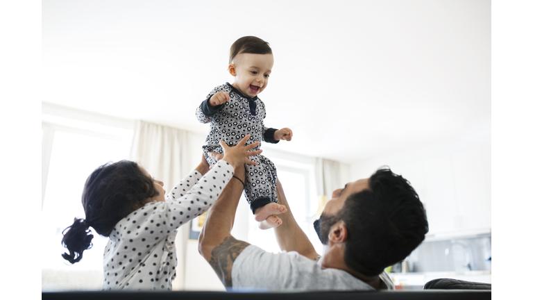 Father and daughter lifting toddler at home
