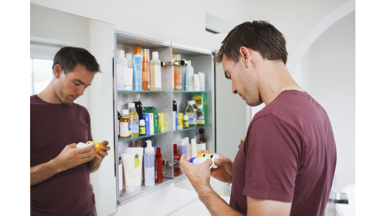 Man looking at bottles from medicine cabinet