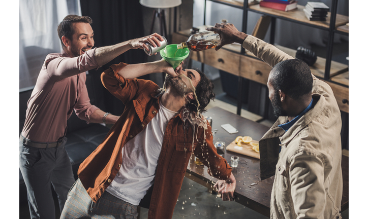 high angle view of man drinking from funnel while friends pouring alcohol beverages