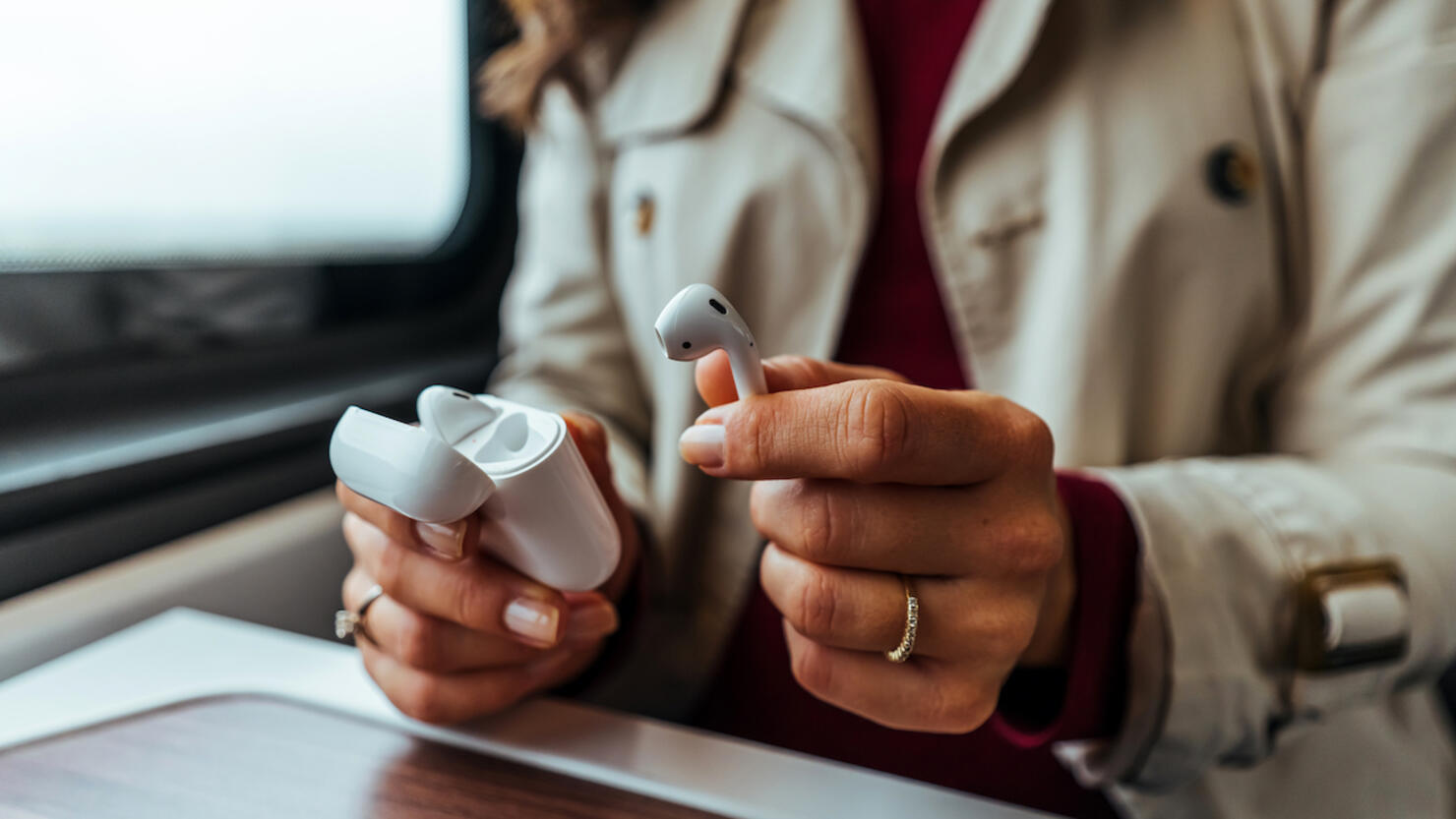 Close-up of a woman taking out a white wireless earbud from his charging box.