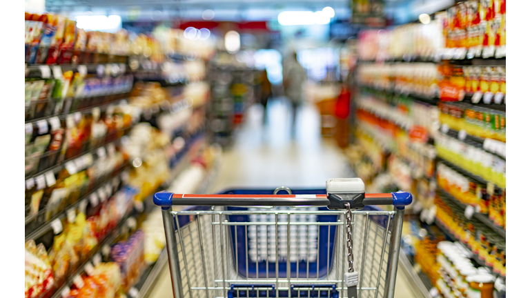 A shopping cart by a store shelf in a supermarket