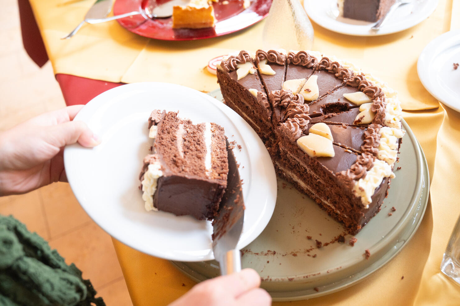 A person serves a piece of chocolate cake at a celebration.
