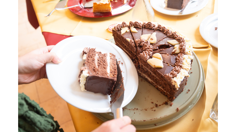 A person serves a piece of chocolate cake at a celebration.
