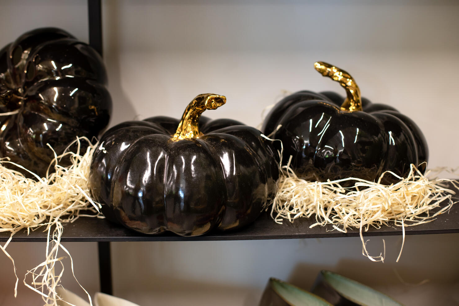 Festive Decorative black Jack-o'-lanterns on shelf. Holiday Decor porcelain pumpkins for celebration of the harvest season or Halloween. Autumn composition at home. Ceramic Large Halloween pumpkin.