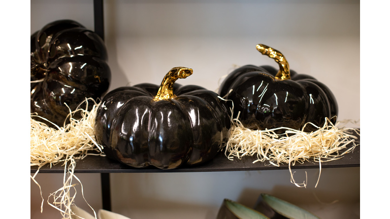 Festive Decorative black Jack-o'-lanterns on shelf. Holiday Decor porcelain pumpkins for celebration of the harvest season or Halloween. Autumn composition at home. Ceramic Large Halloween pumpkin.