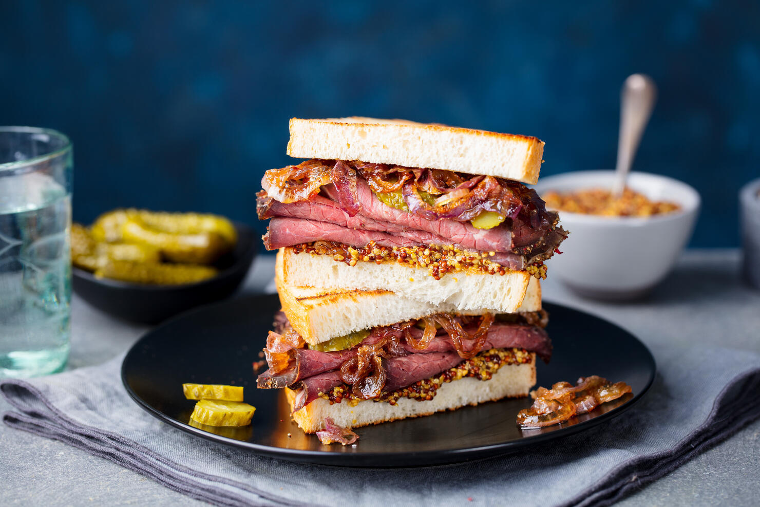 Roast beef sandwich on a plate with pickles. Copy space.