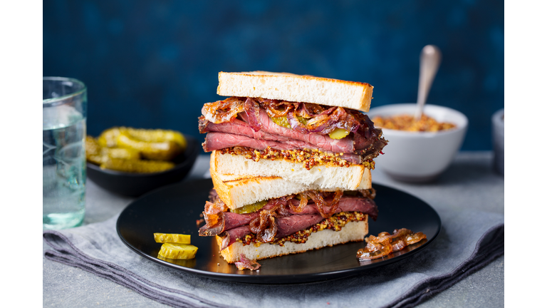 Roast beef sandwich on a plate with pickles. Copy space.