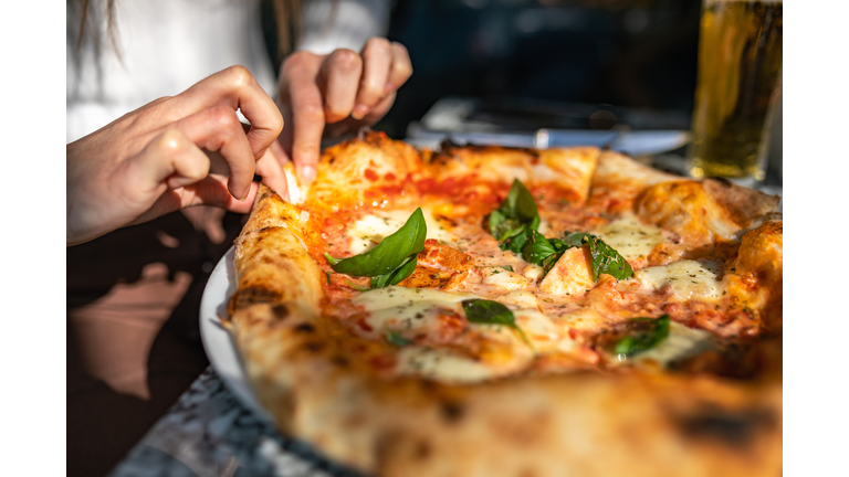 Unrecognizable woman taking a slice of pizza