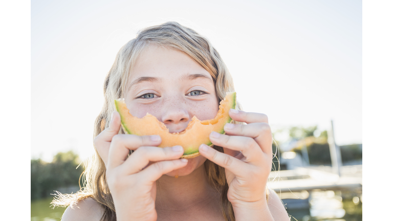 Caucasian girl eating cantaloupe slice