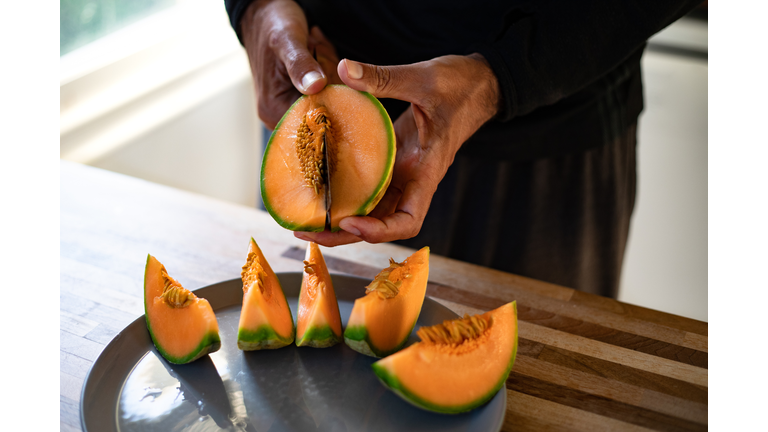 A man removing the seeds of a cantaloupe, melon.