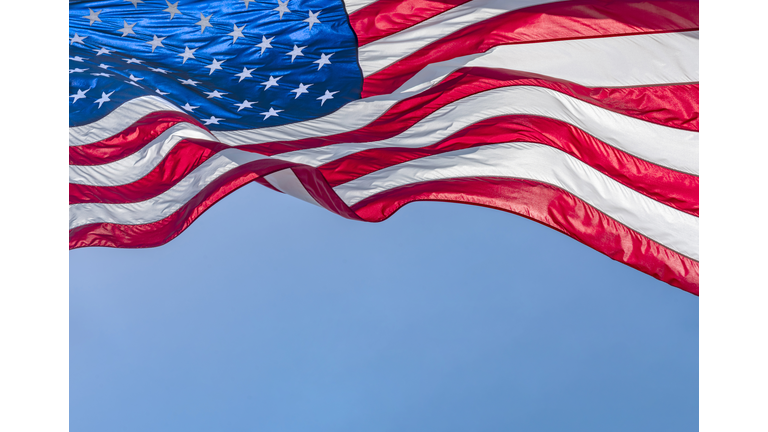 Low angle view of American flag waving in wind against clear sky