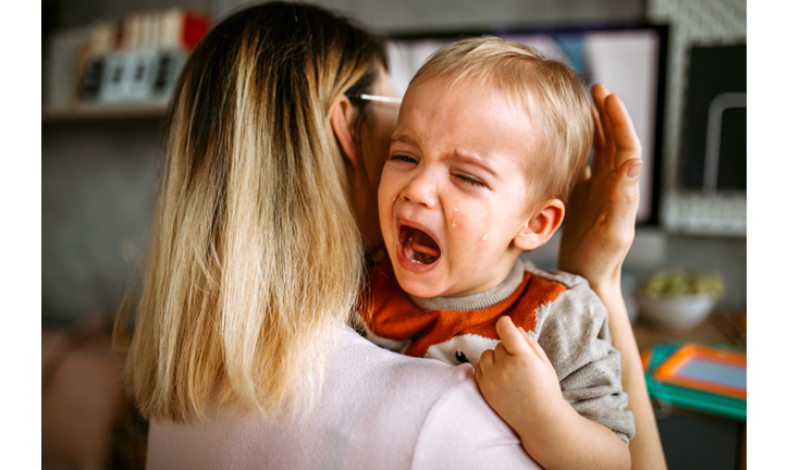 Baby boy is crying while mother holding him in arms