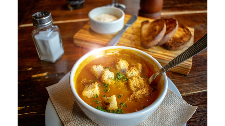 Sopa de calabaza con trozos de pan tostado.