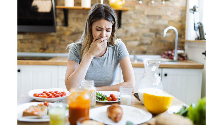 Woman feeling sick during breakfast time in dinning room
