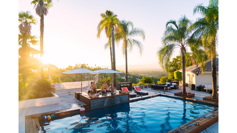 Young group of friends staying in a luxury villa enjoying the hot tub as the sun sets