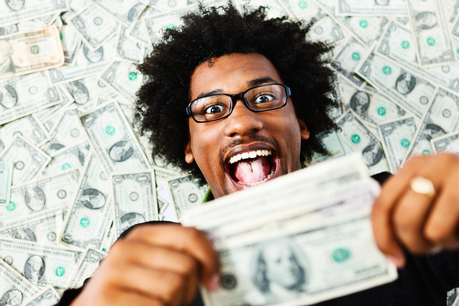 Overjoyed young man surrounded by US dollars