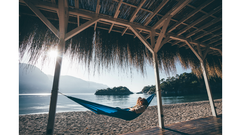 Woman relaxing in hammock on beach