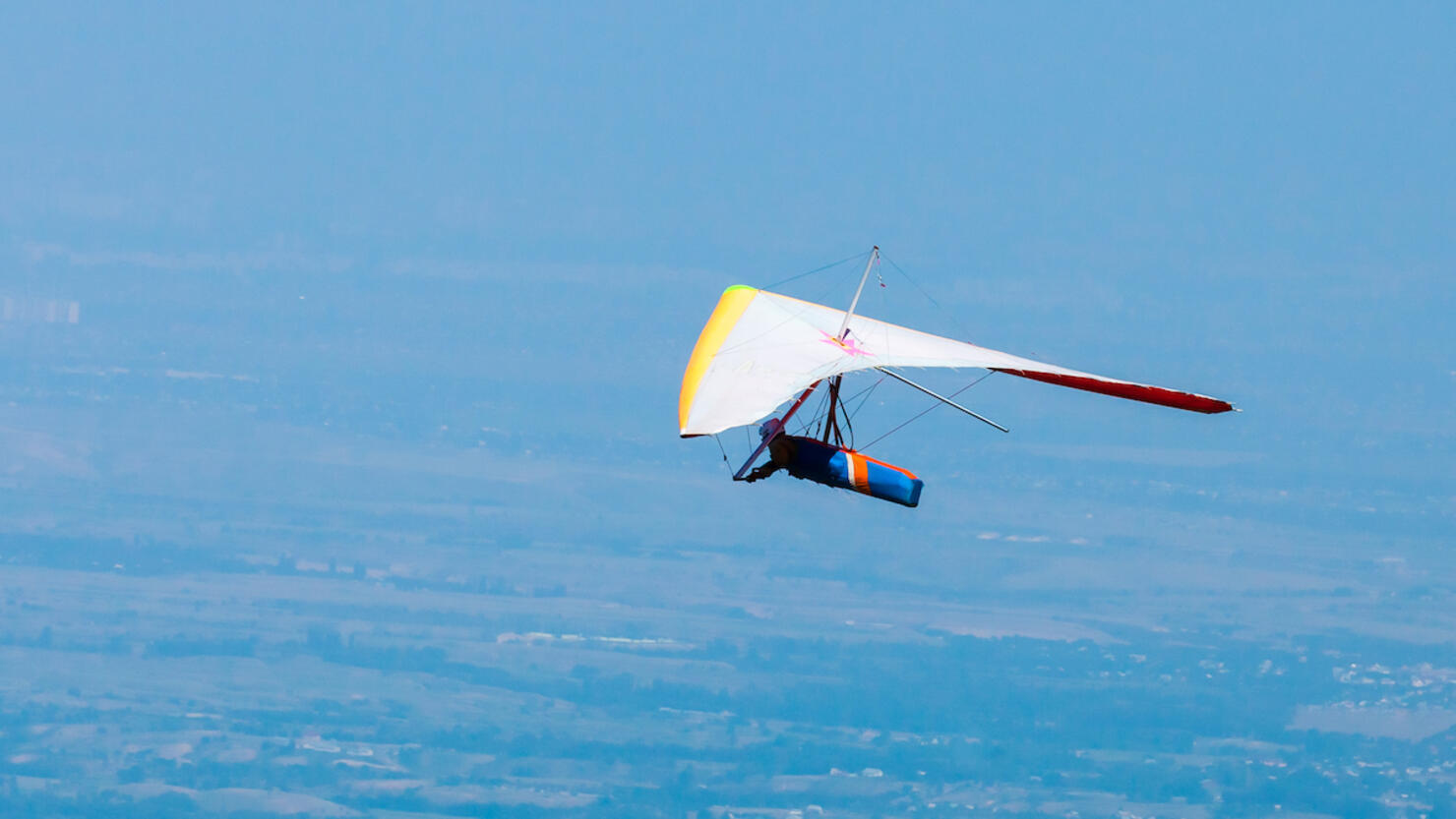 Low angle photo of hang glider flying in clear bright sky