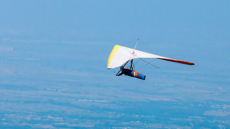 Low angle photo of hang glider flying in clear bright sky