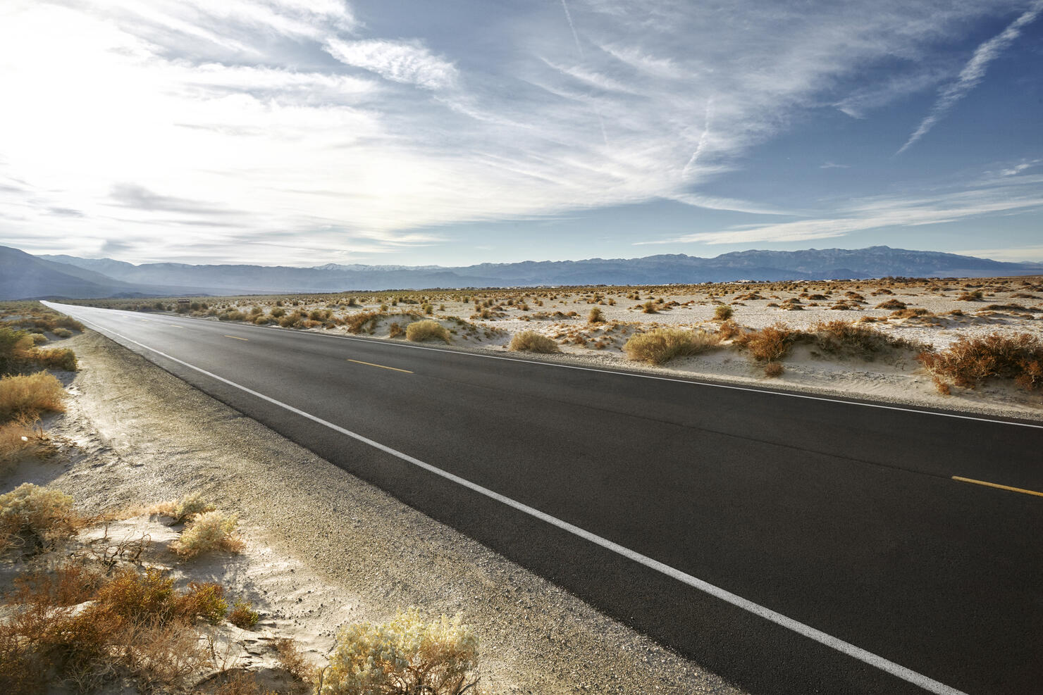 Empty road in desert landscape with distant mountains