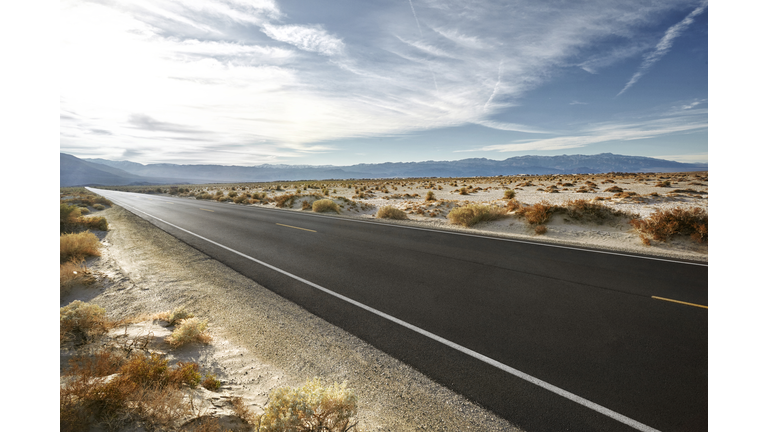 Empty road in desert landscape with distant mountains