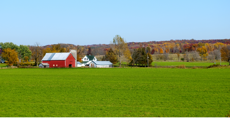 Landscape view of red Midwestern dairy farmhouse and land