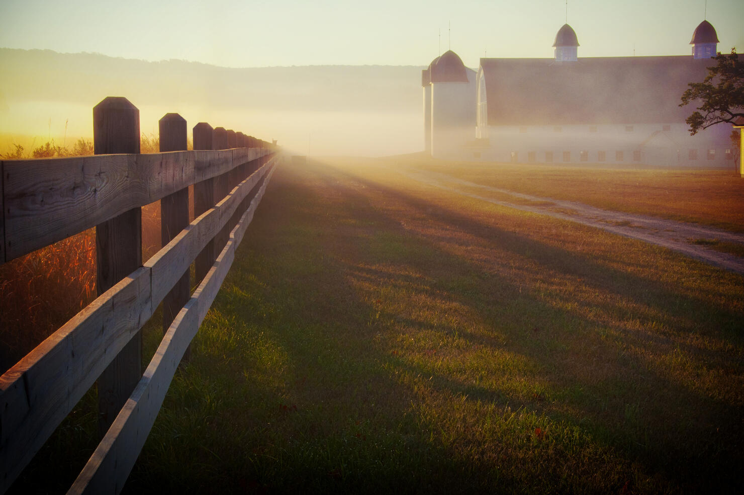 Foggy morning farm fence at sunrise