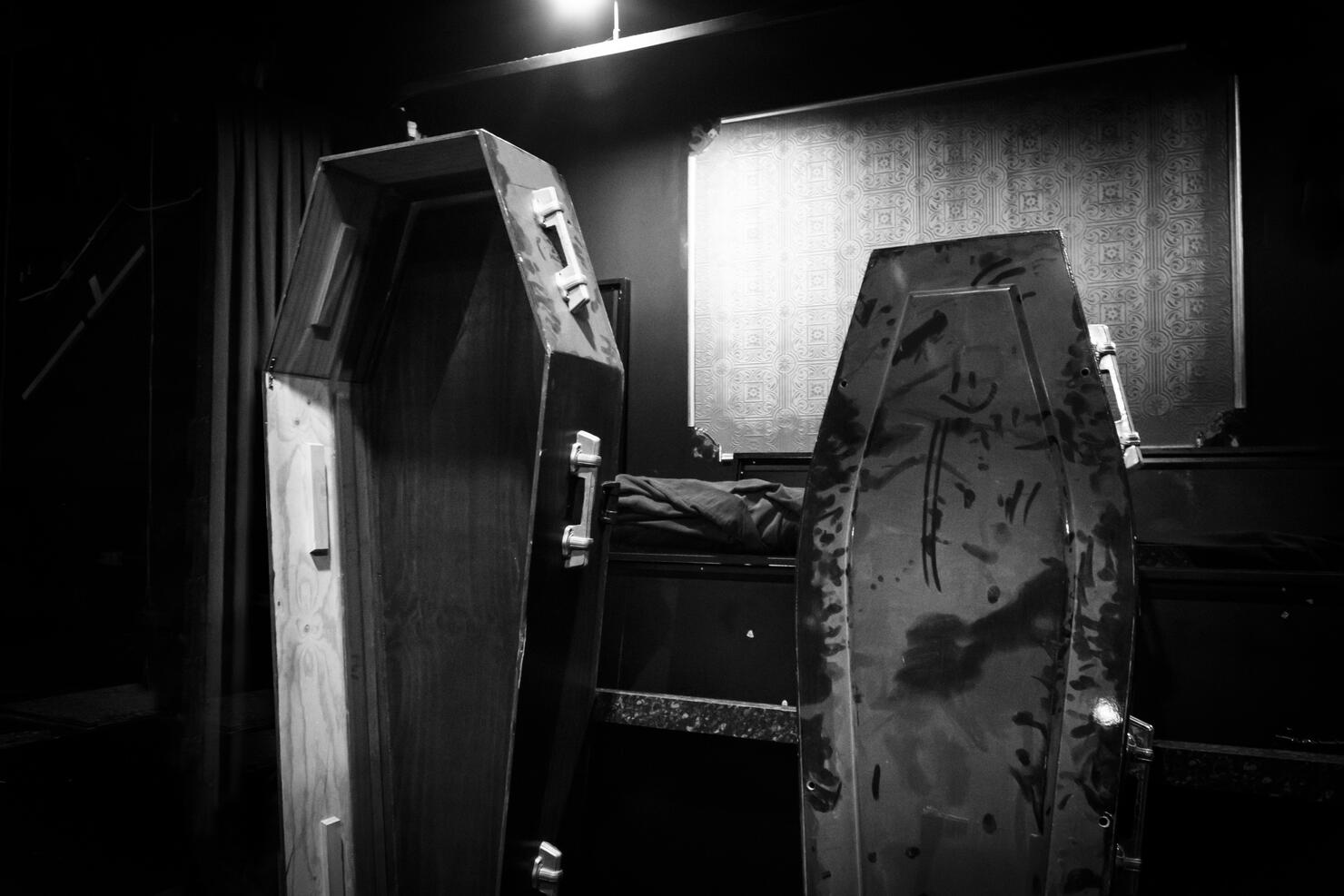 Two dusty coffins leaning against a wall