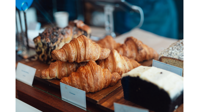 Close-up of fresh croissants and loaf cake displaying on counter at bakery