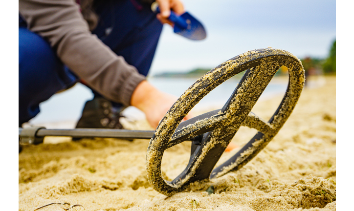 Man with metal detector on sea beach