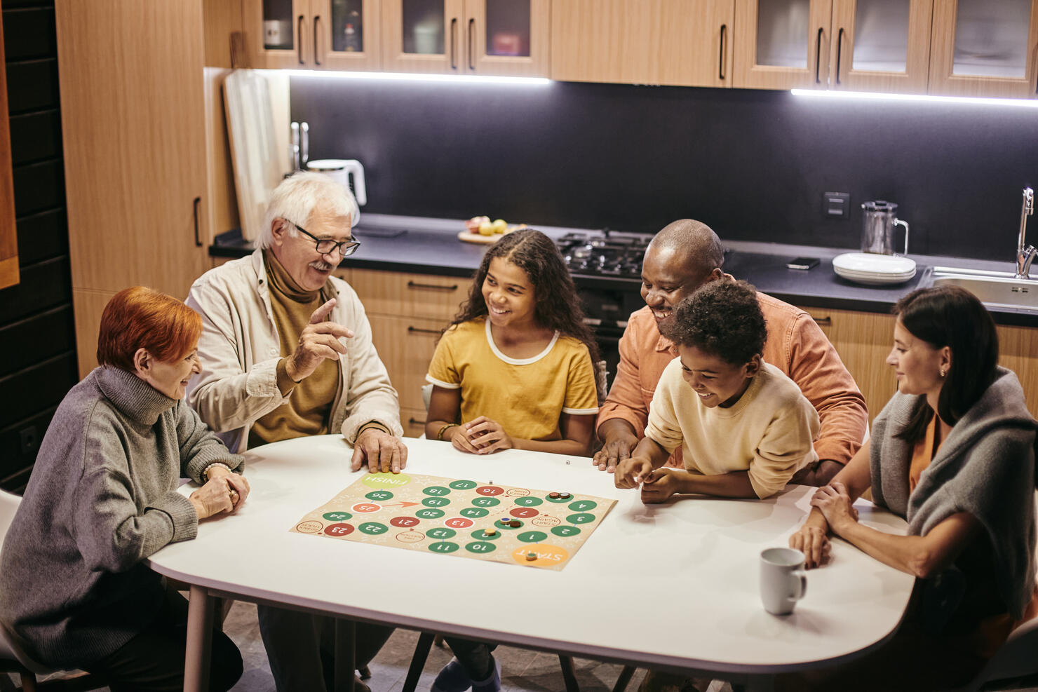 Large happy multiracial family playing board game by table