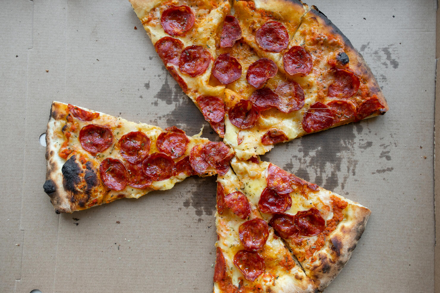 Delicious Italian pizza in a pizza box and a delivery box, on the table in a pizzeria. Sliced pizza slice with tomatoes, pepperoni sausage and cheese. The concept of unhealthy lifestyle, overeating, junk food, fast food. Delivery to your home or work.