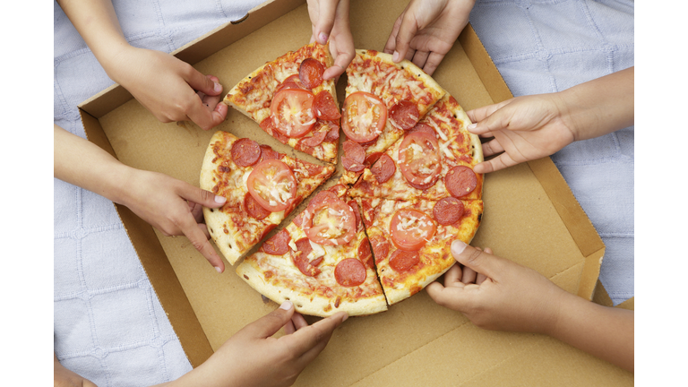 Children's hands taking pizza slices out or box