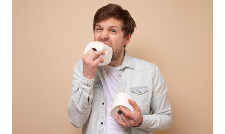 Funny caucasian young man eats a toilet paper. He forgot to buy food in coronavirus panic.