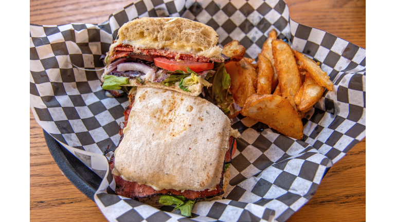 Roast beef panini with a side of potato wedges in a greaseproof paper lined serving basket