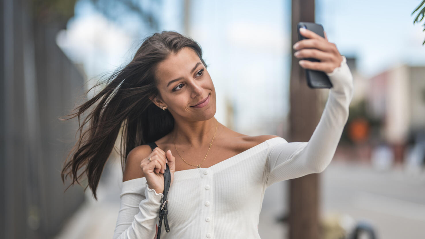 Smiling woman taking selfie on smart phone in city