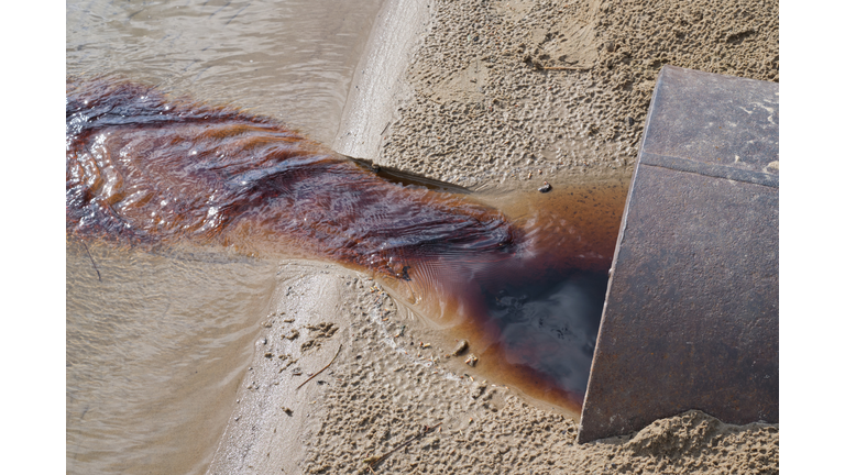 waste water running  from a out of a metal pipe onto pond. Sewage drains into the river. Environmental pollution. Ecological catastrophe and disaster.