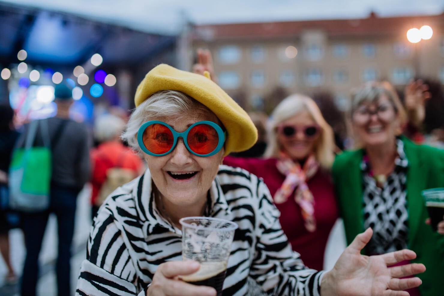 Cheerful senior friends enjoying outdoor night concert in city.