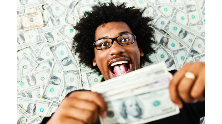 Overjoyed young man surrounded by US dollars